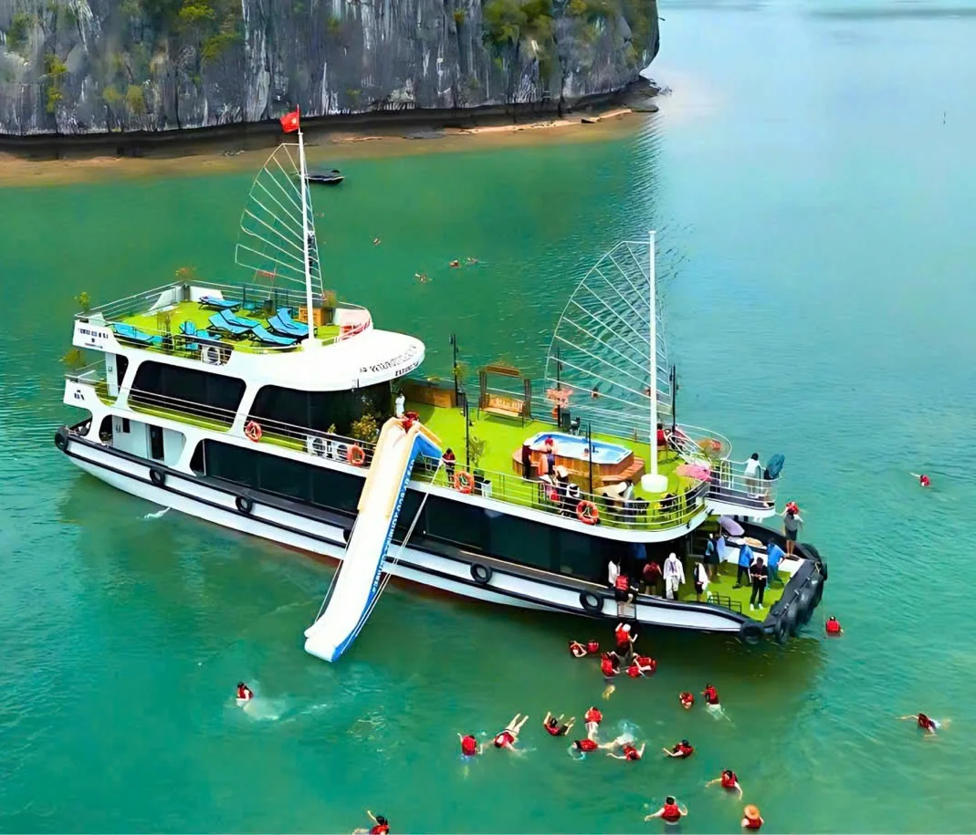 Lan Ha Bay tour boat with guests swimming in emerald water